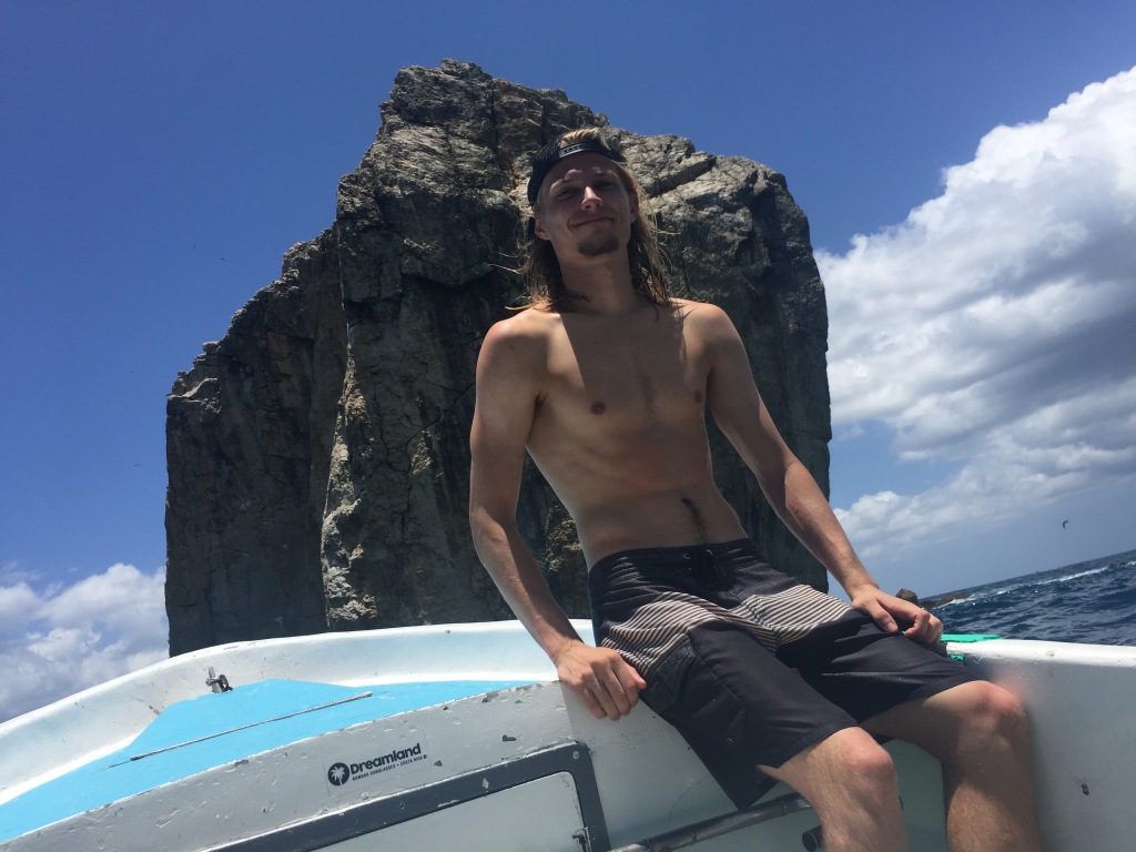 Evan Quarnstrom sits on the rail of a boat at Roca Bruja in Costa Rica.